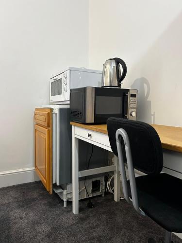 a desk with a microwave and a toaster oven at EGHAM LOVELY STUDIO SELF CONTAINED 2 mins station in Egham