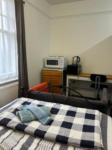 a bed with a checkered blanket and a microwave at EGHAM LOVELY STUDIO SELF CONTAINED 2 mins station in Egham