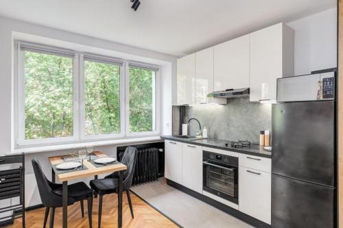una cucina con mobili bianchi e un tavolo con sedie di Złota 77 by NYX Apart a Skorka