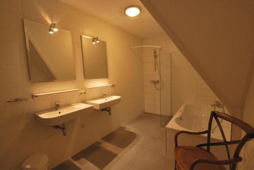 a bathroom with two sinks and a mirror at Beachvilla Royaal Classic met Sauna - 10 personen in Holle Poarte
