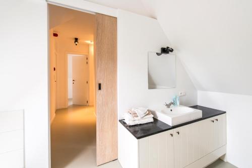 a white bathroom with a sink and a mirror at Lozer Lodge Vakantiewoning in Kruisem