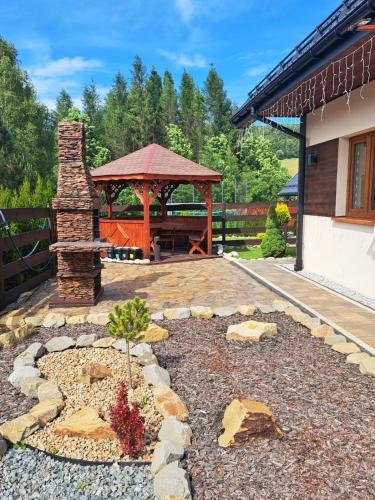 a garden with a gazebo and a stone patio at Całoroczne Domki Wypoczynkowe - Osada pod Górą in Ustrzyki Dolne