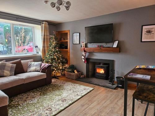 a living room with a fireplace and a christmas tree at Ghillies Cottage, Loch Ness in Milton