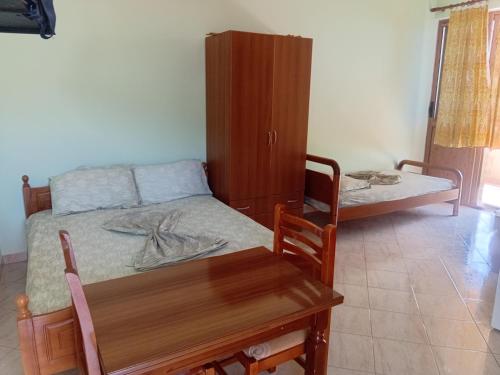 a bedroom with a bed and a table and a cabinet at Telo Shehu Holiday Home in Radhimë