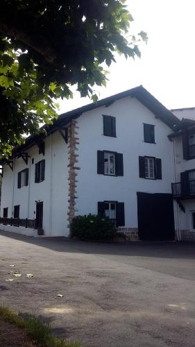 a white house with black windows and a driveway at maison garroenea in Sare