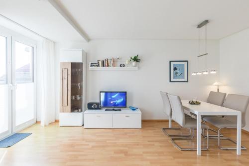 a white living room with a table and a tv at Sünnslag Wohnung 113 in Boltenhagen
