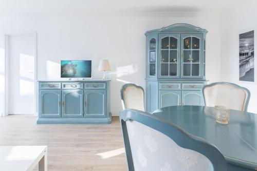 a dining room with a blue cabinet and a table at Sünnslag Wohnung 114 in Boltenhagen