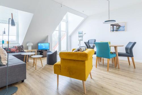 a living room with a yellow chair and a table at Sünnslag Wohnung 129 in Boltenhagen