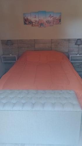 1 cama con edredón de naranja en un dormitorio en Cabaña Ruca Malen, en Tandil