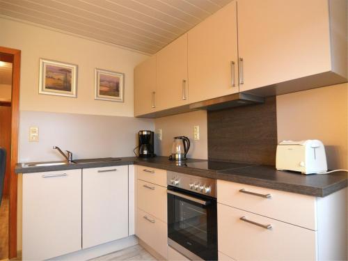 a kitchen with white cabinets and black counter tops at Gemütliche Wohnung für 4 Personen in Medebach