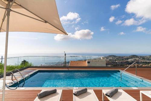 a swimming pool on top of a building with an umbrella at OurMadeira - Vila da Portada in Funchal