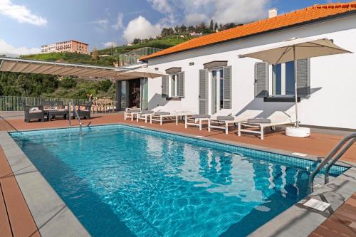 a swimming pool with chairs and a house at OurMadeira - Vila da Portada in Funchal