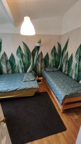 two beds in a room with a mural of leaves at Studio sur jardin in Villejuif