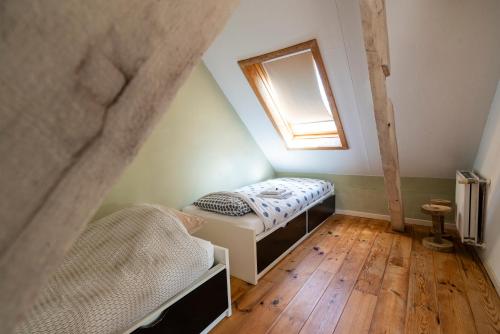 a attic room with a bed and a window at Lozer Lodge Vakantiewoning in Kruisem
