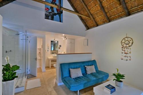 a living room with a blue couch and a bathroom at BonBini Guest House in St Francis Bay