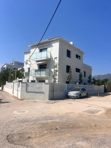a white building with a car parked in front of it at Camping Joncar Mar in Roses