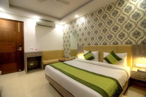 a bedroom with a large bed with a green blanket at Almati Hotel - Near Delhi Airport With - free Airport Pickup in New Delhi