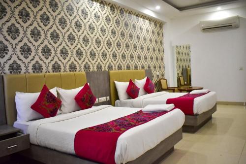 two beds in a hotel room with red and white pillows at Almati Hotel - Near Delhi Airport With - free Airport Pickup in New Delhi