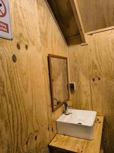 a bathroom with a sink and a mirror on a wooden wall at Isla yu backpacker in Puerto Natales