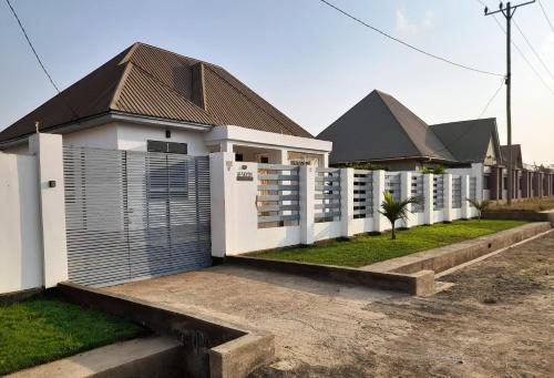 a white house with a fence in front of it at Beskydy Holiday Rentals in Mbeya