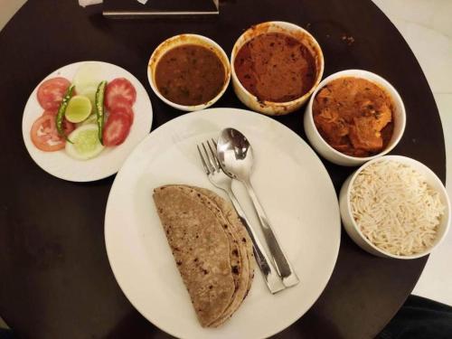 a table with plates of food and bowls of food at Hotel Almora BY The ELEVATE Group Near Delhi INTERNATIONAL Airport WIth- Free AIRPORT Pickup in New Delhi