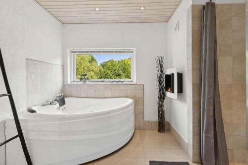 Un baño blanco con bañera y ventana. en Lovely Holiday Home In Helberskov, en Hadsund