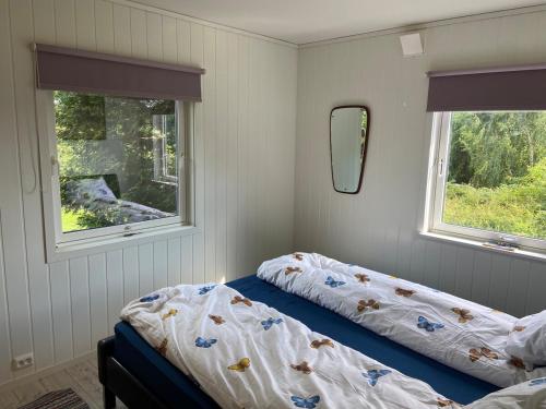a bedroom with two beds and two windows at Fjord Home Near Preikestolen in Strand