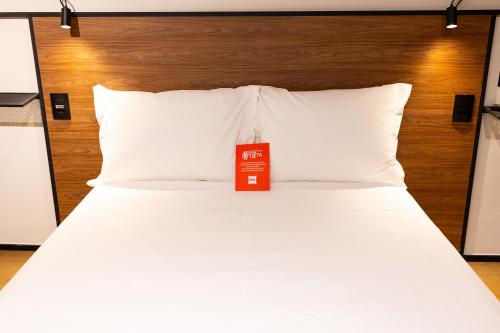 a white bed with a red sign on it at Ibis Votuporanga in Votuporanga