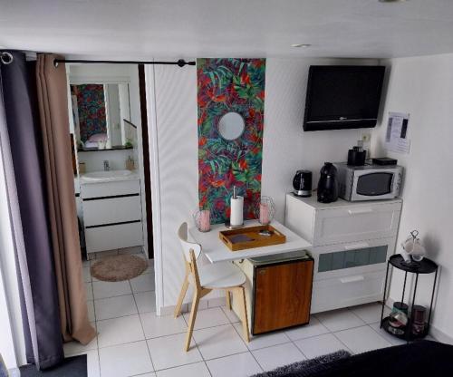 Una pequeña cocina con una mesa y un microondas. en Agréable chambre pour 2 avec salle de bain et terrasse privées, en Fagnières