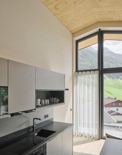 a kitchen with white cabinets and a large window at Neueröffnung ELVA PREMIUM APARTMENT HOTEL inklusive Sommerpass STUBAI SUPER CARD in Neustift im Stubaital