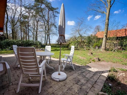 a table and chairs and an umbrella on a patio at Bungalow in Holten near Forest Trails in Holten