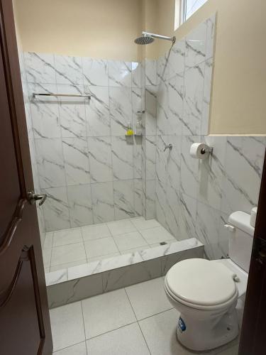 a white bathroom with a shower and a toilet at Lugar acogedor en Limoncocha - Amazonia in Limoncocha