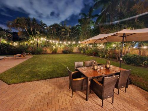 una mesa de madera con sillas y una sombrilla en el patio en Fox Island Heated Spa- Downtown & Beach, en Fort Lauderdale