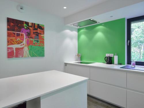 a kitchen with white cabinets and a green wall at Jalhay Pondside Forest Home in Jalhay