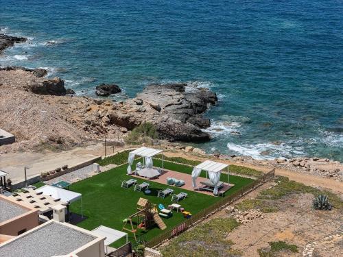 una vista aérea de una casa con jardín y océano en Lovely seaside apartments, walking distance to the beach & amenities!, en Panormos Rethymno