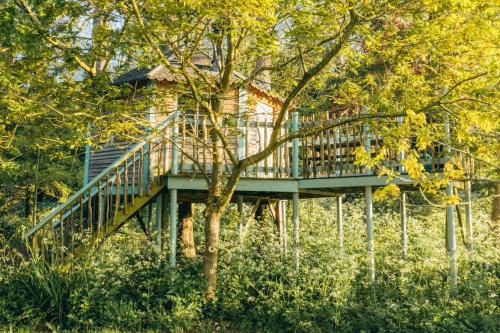 a tree house with a deck in the woods at West Lexham Retreat in Kings Lynn