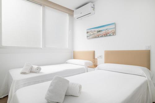 two beds in a white room with a window at Apartamentos Almadraba in Zahara de los Atunes