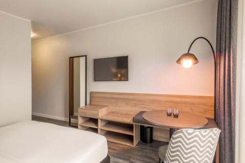 a hotel room with a bed and a table and a desk at Hotel Münster Kongresscenter affiliated by Meliá in Münster