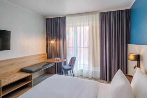 a hotel room with a bed and a table at Hotel Münster Kongresscenter affiliated by Meliá in Münster