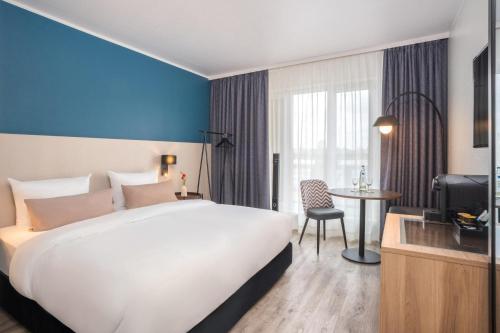 a hotel room with a large bed and a table at Hotel Münster Kongresscenter affiliated by Meliá in Münster