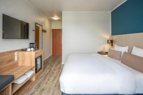 a bedroom with a large white bed and a television at Hotel Münster Kongresscenter affiliated by Meliá in Münster