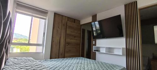 a bedroom with a bed with a television and a window at Senderos in Pereira