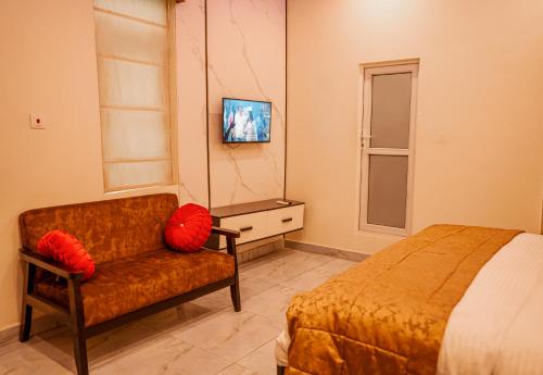a bedroom with a bed and a chair with red pillows at Apartment 79 Hotel & Suite in Ikeja
