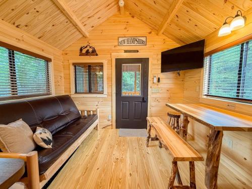 a living room with a leather couch in a wooden cabin at SaunaHaus - Log Cabin plus Private Sauna by the Brook in Lincoln