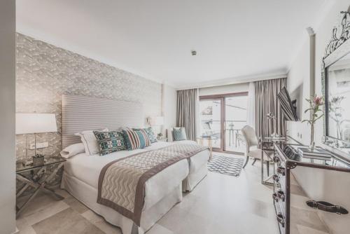 a large bedroom with a large bed and a desk at Puente Romano Marbella in Marbella
