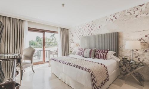 a bedroom with a bed and a desk and a piano at Puente Romano Marbella in Marbella