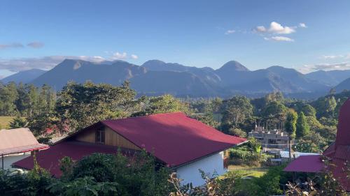 a house with a red roof with mountains in the background at BIOSFERA LODGE GLAMPING tipi 2 personas in Oxapampa