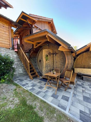 a wooden house with a table and chairs in front of it at Glamping Medvedjek - Nočitev v vinskem sodu in Velika Loka