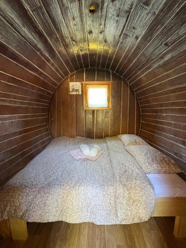 a small bed in a wooden room with a window at Glamping Medvedjek - Nočitev v vinskem sodu in Velika Loka