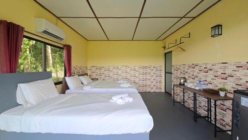 two beds in a room with yellow walls at Khao Sok Horizon in Ban Bang Thong